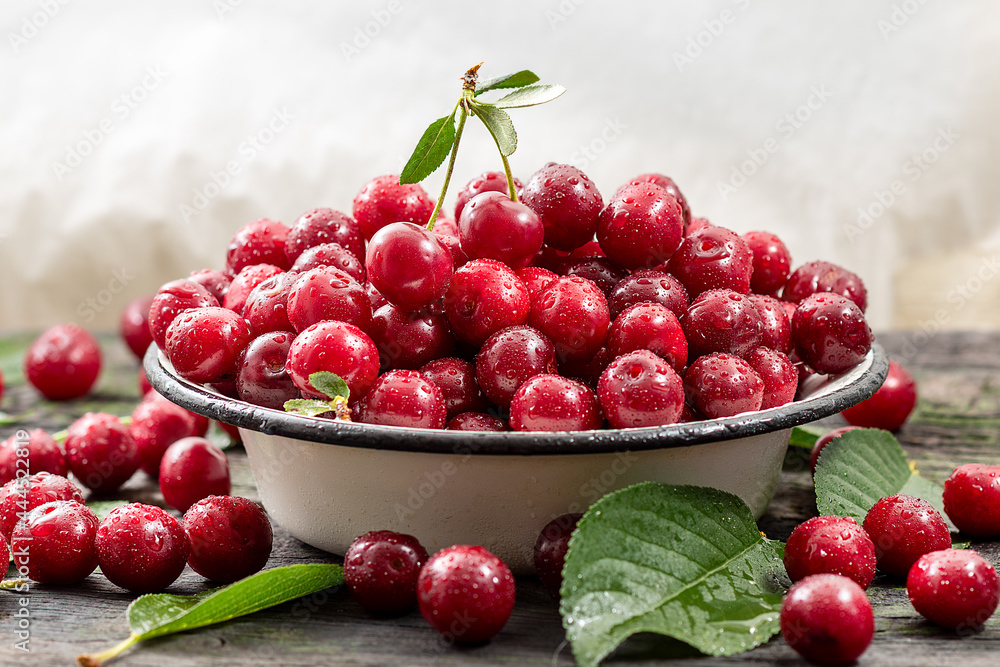 Fresh sweet cherries bowl with leaves on wooden desktop table. water drops on Fresh sour cherry berries Fresh sweet cherries bowl with leaves on wooden desktop table. water drops on Fresh sour cherry berries