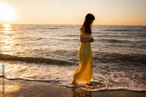 Beautiful woman on the beach at sunset. ​She is enjoying serene ocean nature during travel holidays vacation outdoors. Summer time. #444522851