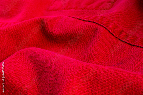 clothing items stonewashed red cotton fabric texture with seams, clasps, buttons and rivets, macro