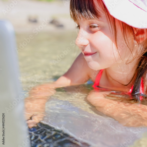 Learning always and everywhere concept. Close up portrait of very happy young girl learning remotely with laptop outdoors in tropical sea.