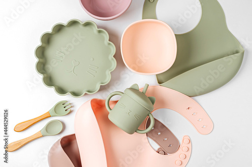 Children's tableware and silicone bibs. Baby accessories. Nutrition and feeding concept. Top view, flat lay photo