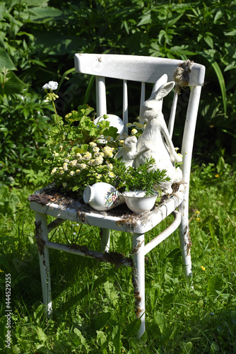 Vintage wooden chair with rabbit figurines in a garden