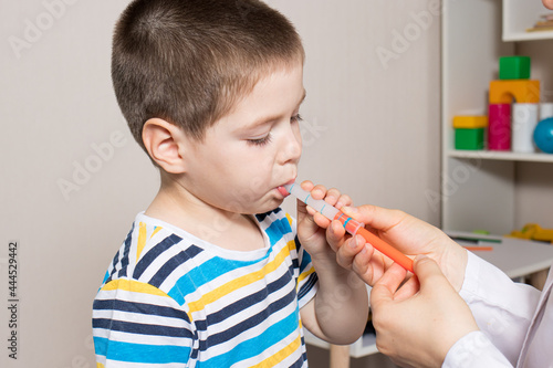 The pediatrician or nurse gives the child syrup in a measuring syringe. Treatment of cough, temperature in children. Paracetamol or ibuprofen for toddlers and preschoolers in pediatrics photo