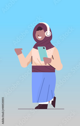 arab schoolgirl using smartphone and listening to music in headphones arabic girl with gadget vertical