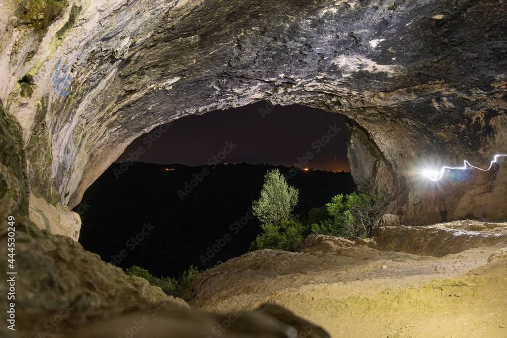 Interior of a cave at night, illuminated with lanterns. 