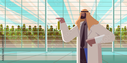 agricultural engineer holding test tube with chemicals arab man farmer researching plants in greenhouse