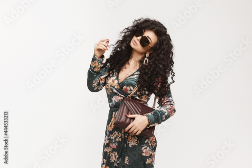 Model girl in trendy dress and sunglasses with modish purse isolated on the white background.