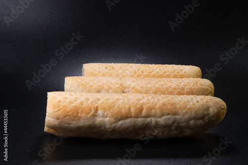 Bun for french hot dog on a black background. Fast food bakery product. production