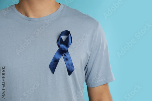 Man with ribbon on light blue background, closeup. Urology cancer awareness