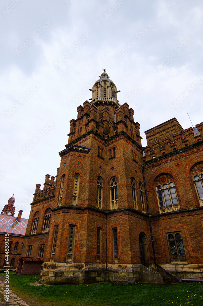 Ancient brown brick building of Chernivtsi University against rainy sky. UNESCO World Heritage Site. Travel and tourism concept. Selective focus with wide angle lens