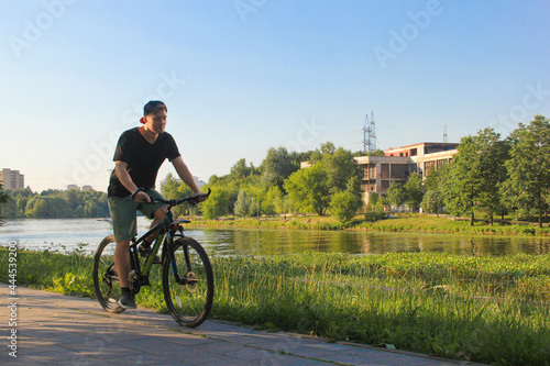 A guy rides a bike in the park. Young fit man during a bike ride on a sunny day
