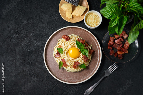 Traditional Italian Pasta Carbonara with bacon, cheese and egg yolk on plate on dark background. Top view Flat lay