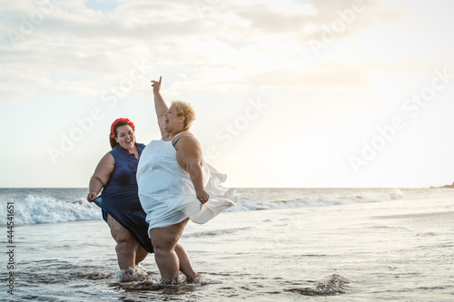 Happy plus size women having fun on the beach during summer vacation - Curvy confident people lifestyle concept photo