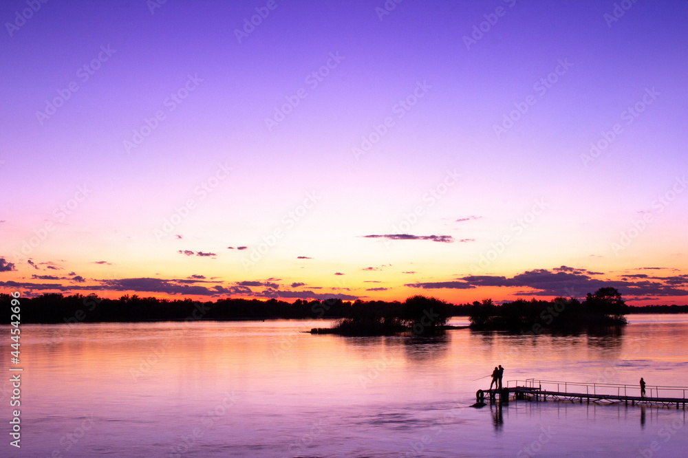 silhouettes of people fishing on the river at sunset silhouettes of people fishing on the river at sunset
