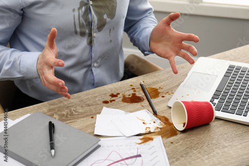 Man with spilled coffee over his workplace and shirt, closeup