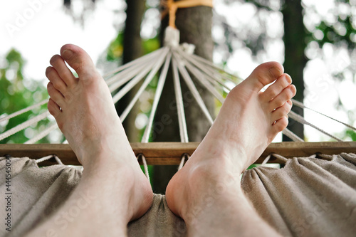 Close-up of male feet on hammock. Man resting on hammock at summer day.
