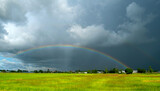 Rainbow after rain over green rice fields sky in Countryside Thailand.
