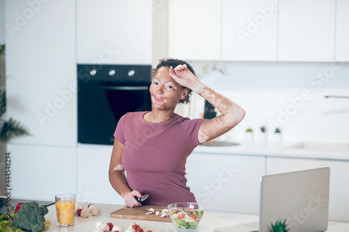 A dark-skinned woman cooking in the kitchen while watching a cookery vlog
