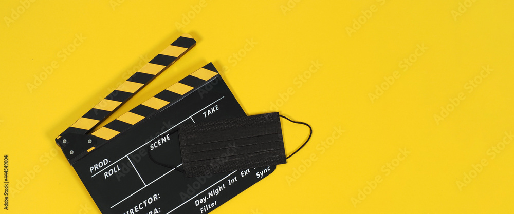 Clapper board or movie slate and black face mask on yellow blackground. Yellow and black color.