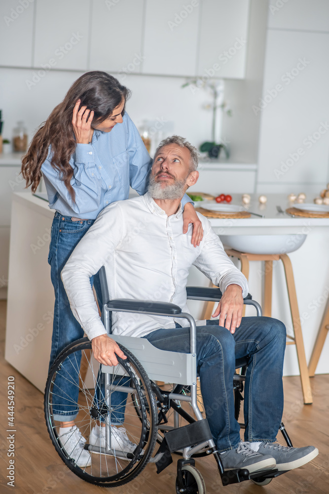 Young long-haired woman smiling nicely to her handicapped hausband and both looking happy Young long-haired woman smiling nicely to her handicapped hausband and both looking happy
