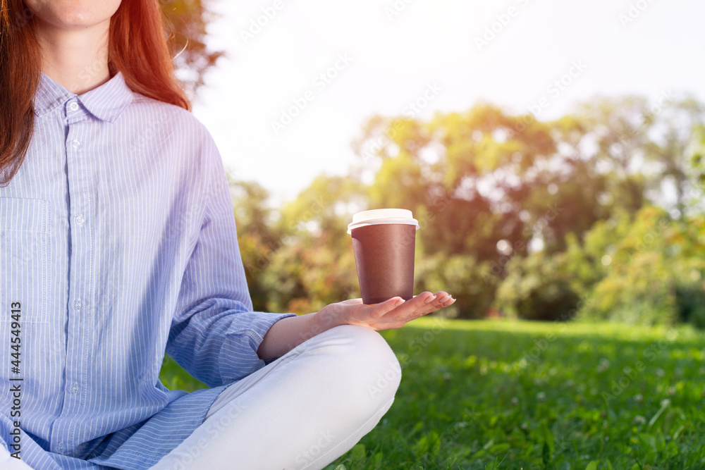 Redhead woman drinking coffee in summer park Redhead woman drinking coffee in summer park