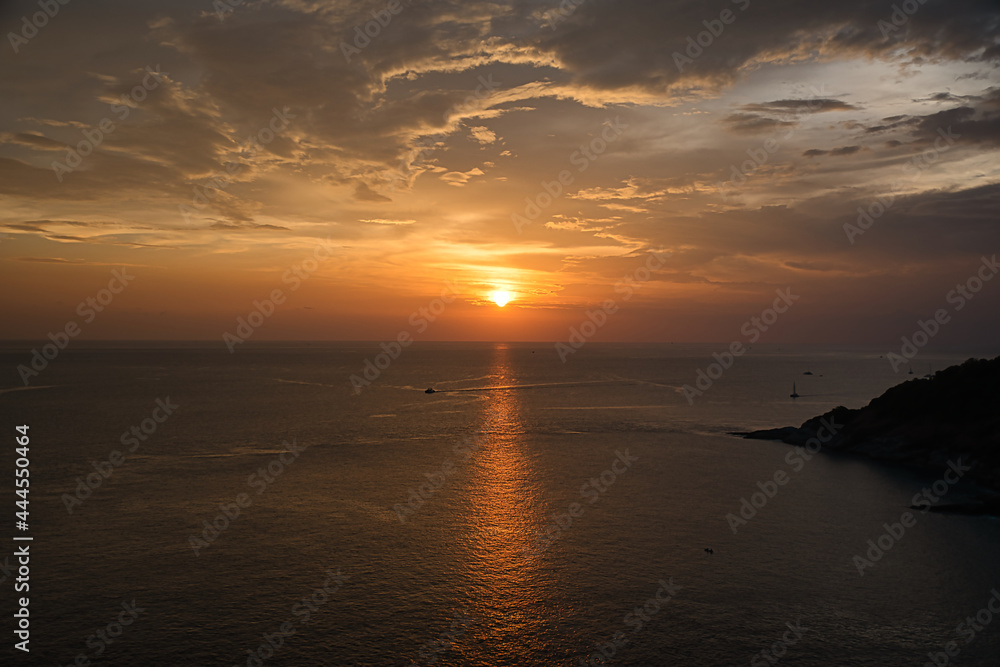 Beautiful, stunning panoramic view of the golden sky and reflections on the Andaman sea during the sunset at Promthep Cape landmark viewpoint in Phuket,