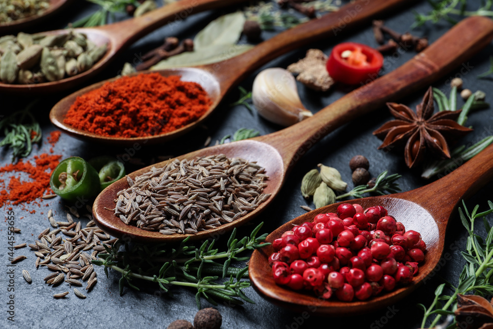 Different natural spices and herbs on black table, closeup Different natural spices and herbs on black table, closeup