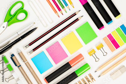 pencils, pens, stickers, scissors, paper clips, crayons, highlighters, clips and an eraser are laid out using the knolling technique on a light background photo