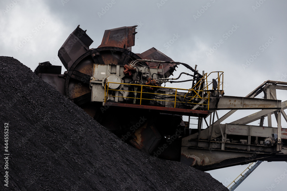 Open-air coal terminal. Close-up. The spinning bucket is hovering over the coal heap.
