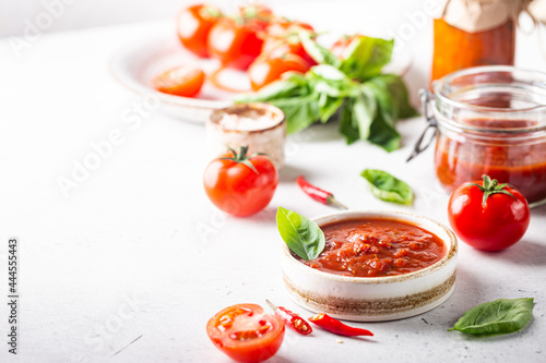 Bowl of italian tomato sauce with basil and fresh tomatoes on white background
