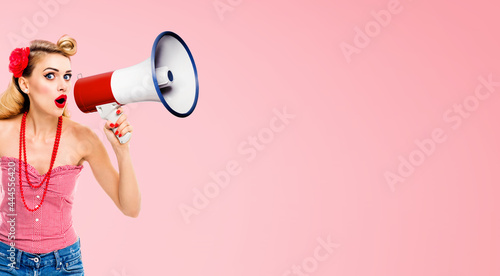 Image of surprised amazed pinup girl. Happy excited woman with open mouth, holding megaphone, pin up style cloth. Retro and vintage. Rose pink colour background.