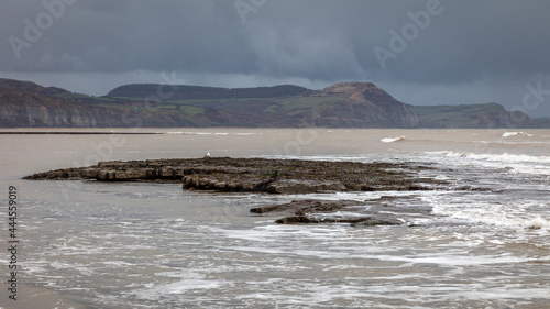 A stormy view of the UK coastline with foreground rocks