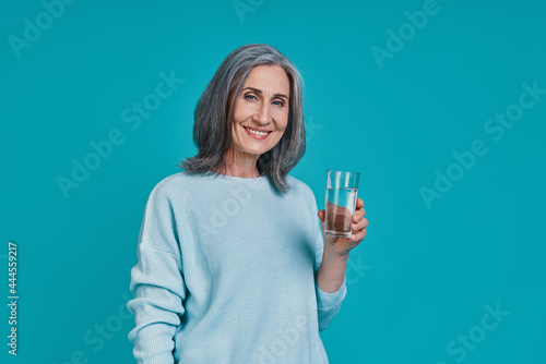 Mature beautiful woman holding glass with water and smiling