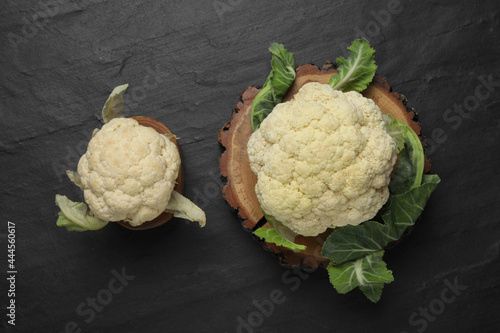 Fresh raw cauliflower cabbages on black table, flat lay