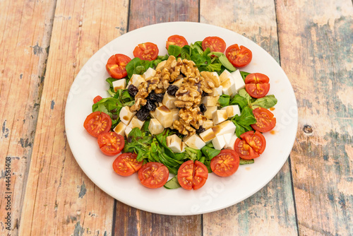 Obraz na plátne salad with chopped cherry tomatoes, diced fresh cheese, hearty chunks of walnuts and raisins on lamb's lettuce shoots