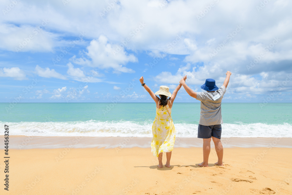 Happy children are back with their hands raised together on a beach at phuket,