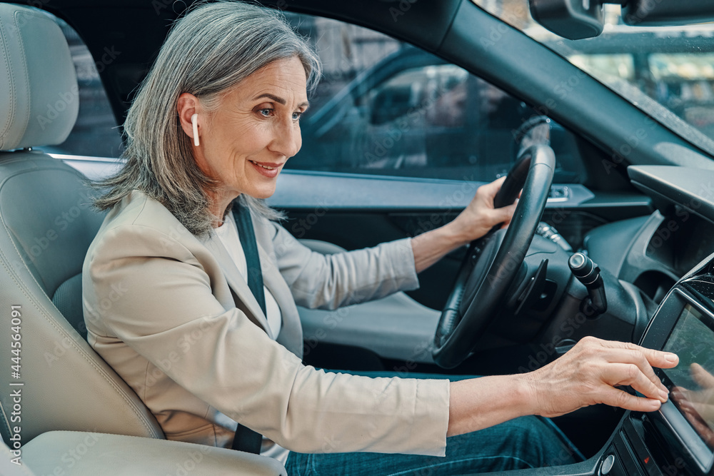 Mature beautiful woman in smart casual wear using global positioning system while driving car