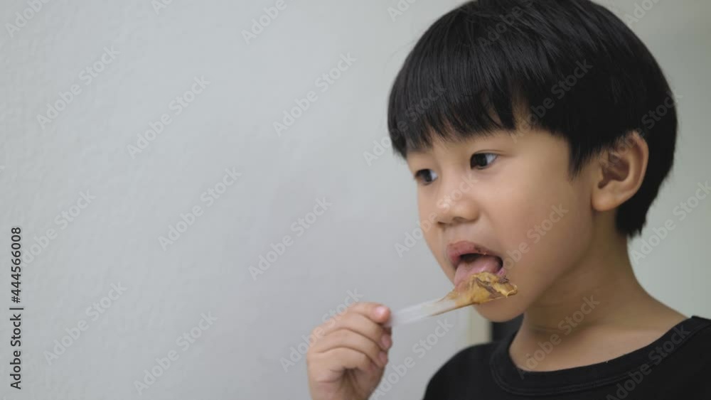 Asian boy licking plastic knife for spreading peanut. A 5 years old kid enjoy a sweet taste of chocolate and nut. Asian boy licking plastic knife for spreading peanut. A 5 years old kid enjoy a sweet taste of chocolate and nut.