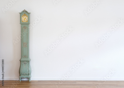 Teal blue grandmother clock for background image with white wall and wood floor
