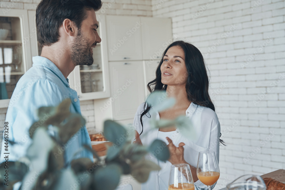 Fototapeta premium Happy young couple smiling while spending time in the domestic kitchen