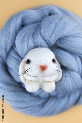 Handmade bunny felted of wool on a beige background.