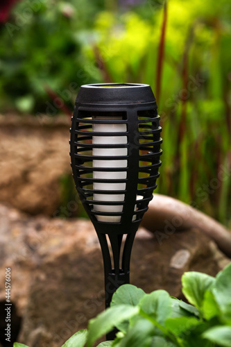 small solar garden light in a flower bed with stones, energy saving and environmetally friendly concept
