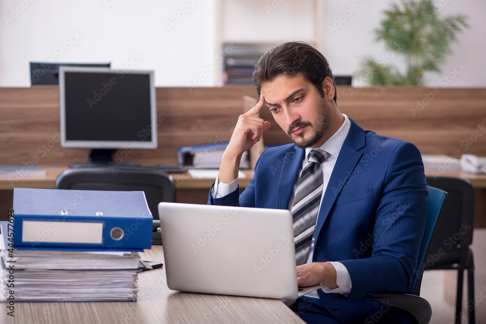 Young male employee and too much work in the office Young male employee and too much work in the office
