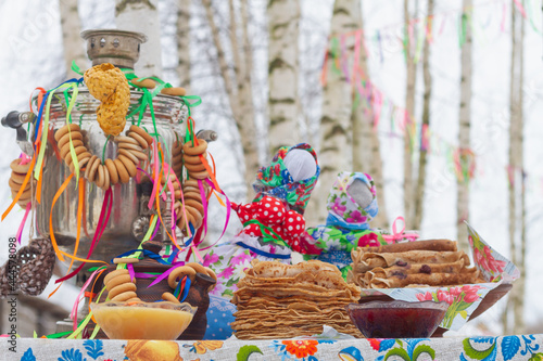 Traditional Russian Maslenitsa decorations for the festive table on Maslenitsa in Russia: Samovar, pancakes, dolls, colorful ribbons, bagels