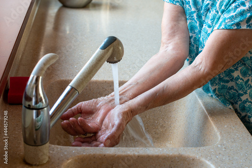 Senior woman hands under cold running water.  Close up. How to stay cool in hot weather.