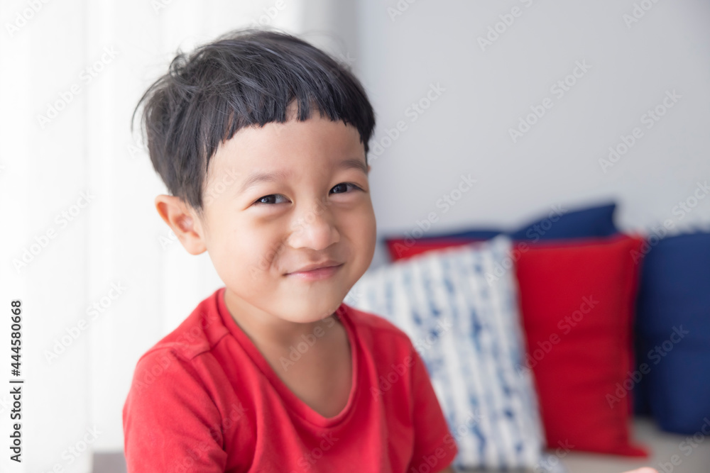Close-up portrait Asian child boy straight black hair wearing a red shirt looking at camera of him make funny faces of happy smiling. Advertising childrens products