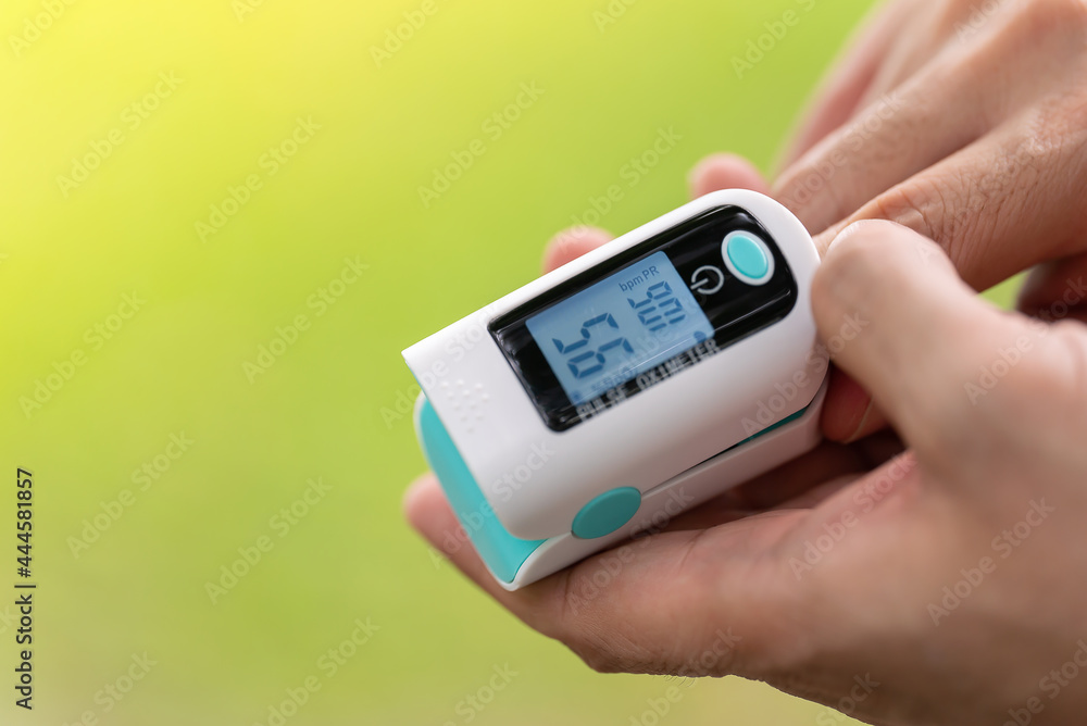 Asian Man measuring oxygen level with modern fingertip pulse oximeter using for measuring heart rate checking oxygen saturation level in the blood diagnosis of Coronavirus or COVID-19 medical concept Asian Man measuring oxygen level with modern fingertip pulse oximeter using for measuring heart rate checking oxygen saturation level in the blood diagnosis of Coronavirus or COVID-19 medical concept