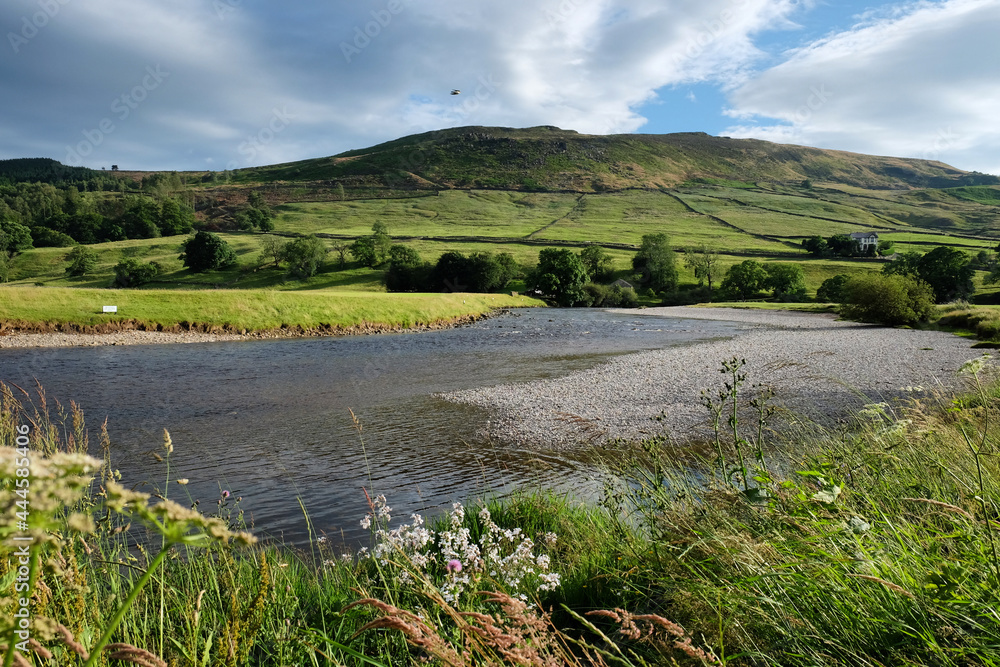 A view looking south along the River Wharfe toward Burnsall and Thorpe Fell, in the Yorkshire Dales, North Yorkshire.