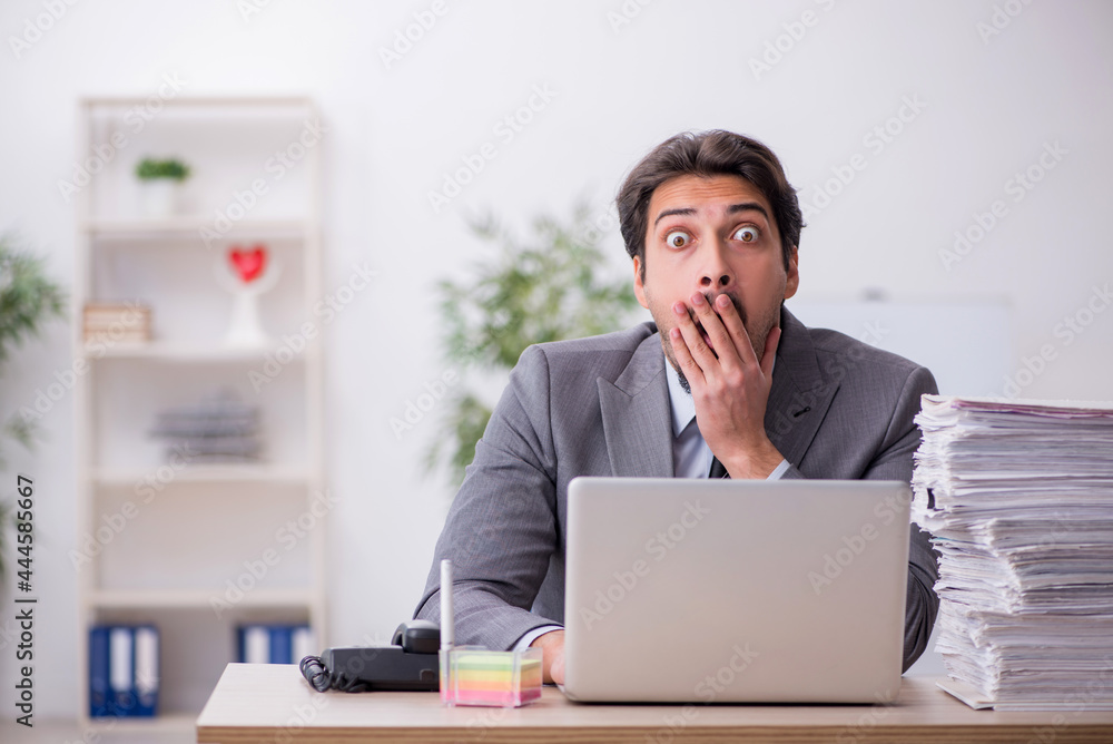 Young male employee and too much work in the office Young male employee and too much work in the office