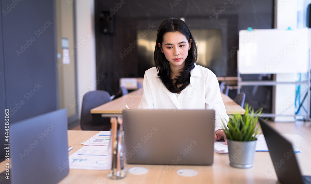 Portrait Asian Businesswoman intends to working with laptop on table at smart modern office. Concept of business work hard. Portrait Asian Businesswoman intends to working with laptop on table at smart modern office. Concept of business work hard.